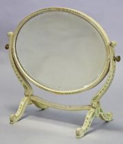 A Regency-style cream-painted oval dressing table mirror with husk-swag decoration and scroll