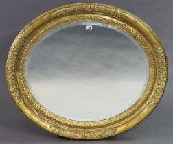 A large gilt frame oval wall mirror with a raised foliate border & inset with a bevelled plate, 84cm