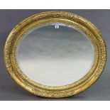 A large gilt frame oval wall mirror with a raised foliate border & inset with a bevelled plate, 84cm