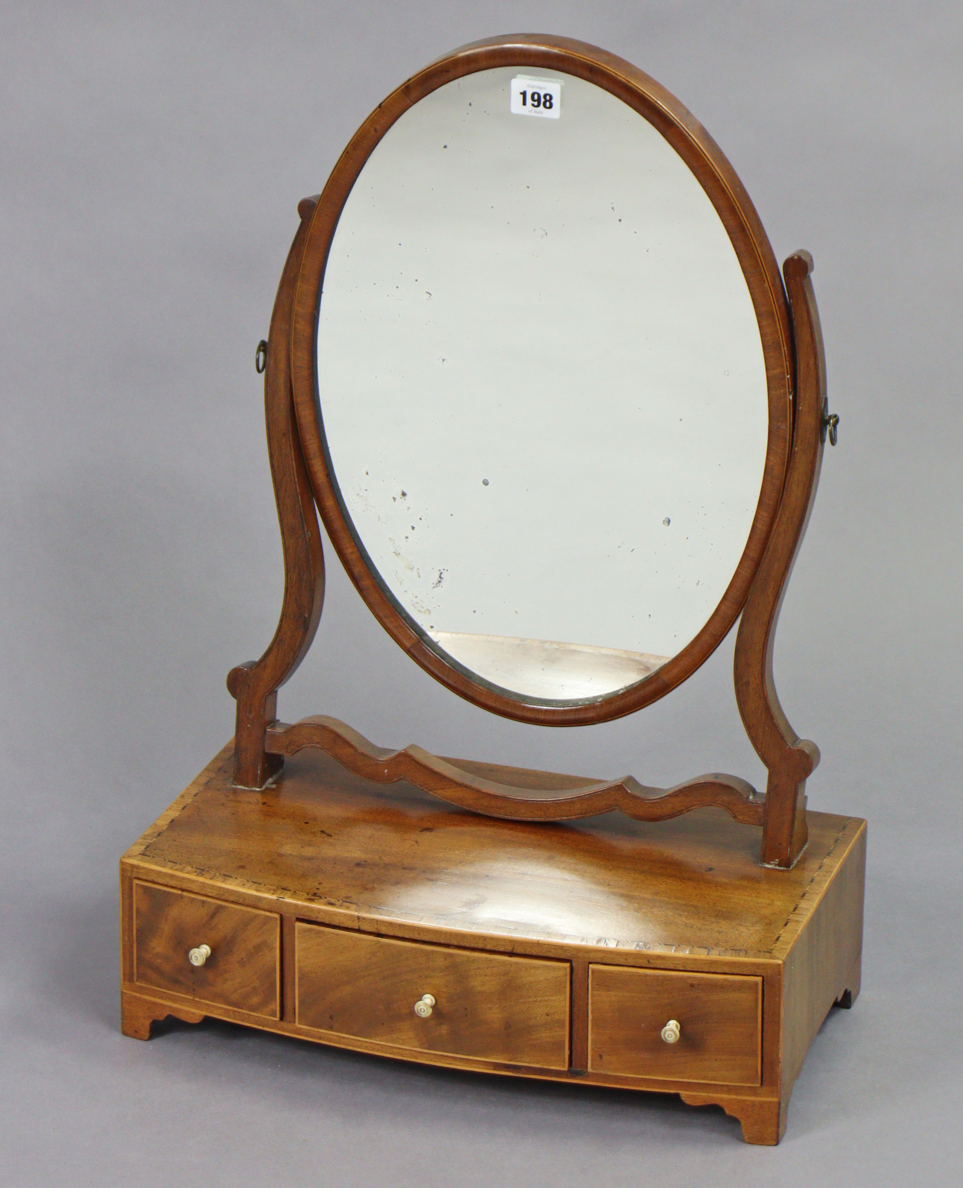 A 19th century inlaid-mahogany oval swing toilet mirror fitted three small drawers to the bow-