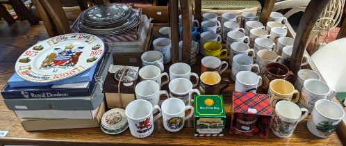 A collection of assorted collector’s plates & commemorative mugs.