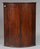 A 19th century mahogany hanging corner cupboard fitted three shelves enclosed by a pair of panel