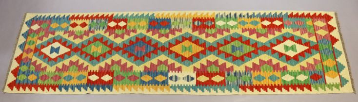 A kelim runner with repeating multicoloured geometric design and narrow border, 298cm x 79cm.