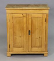 A small pine cupboard fitted two shelves enclosed by a pair of panel doors, & on block feet, 73.75cm