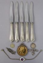A set of five stainless-steel tea knives with loaded silver handles; together with a commemorative c