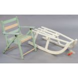 A white painted wooden child’s sledge, 83cm long, and a child’s fold-away chair.