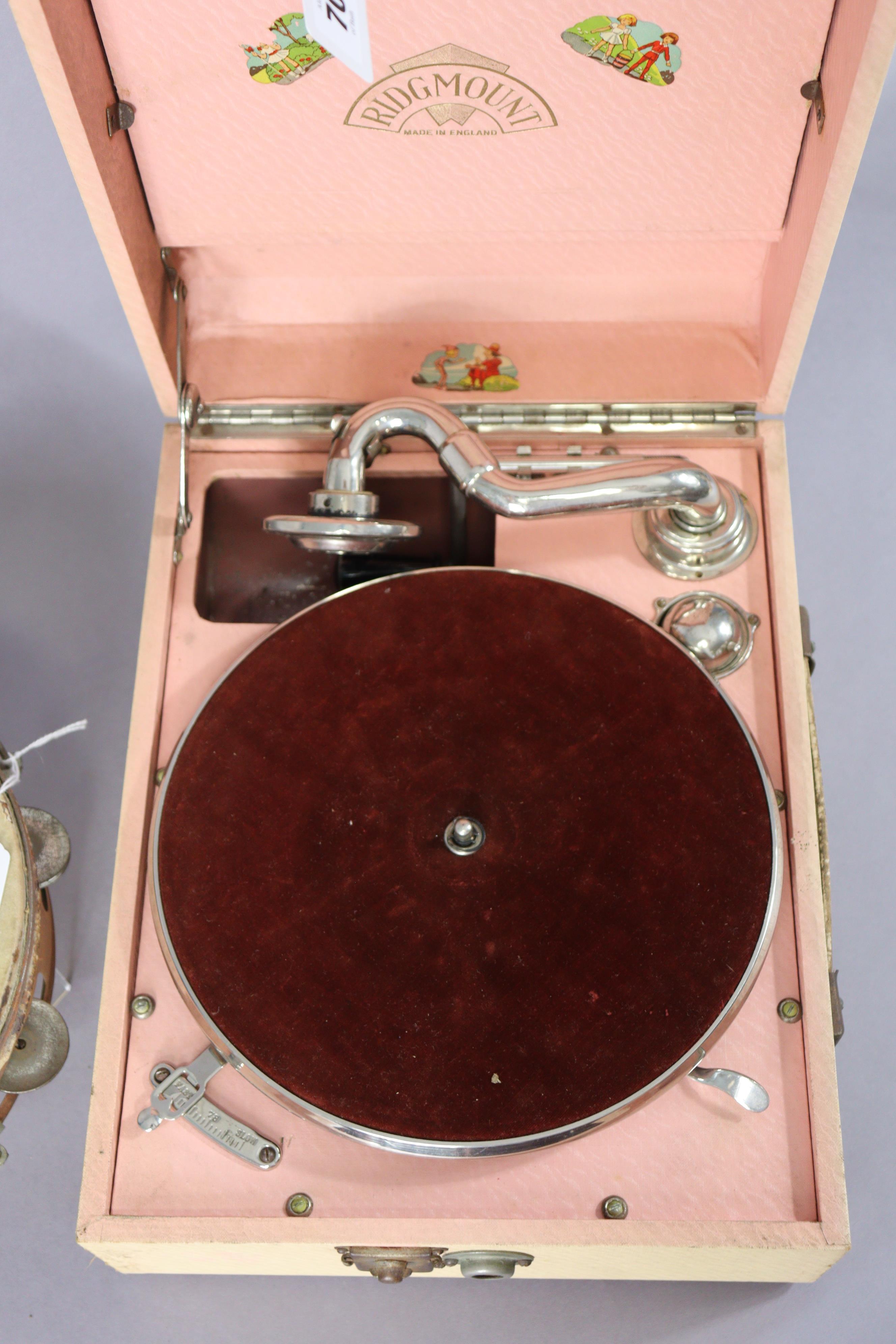 A Ridgmount portable gramophone in a cream finish fibre-covered case; together with a tambourine. - Image 3 of 7