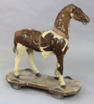 A Victorian hide-covered child’s pull-along toy horse on a wooden oard with castors (waf), 80cm