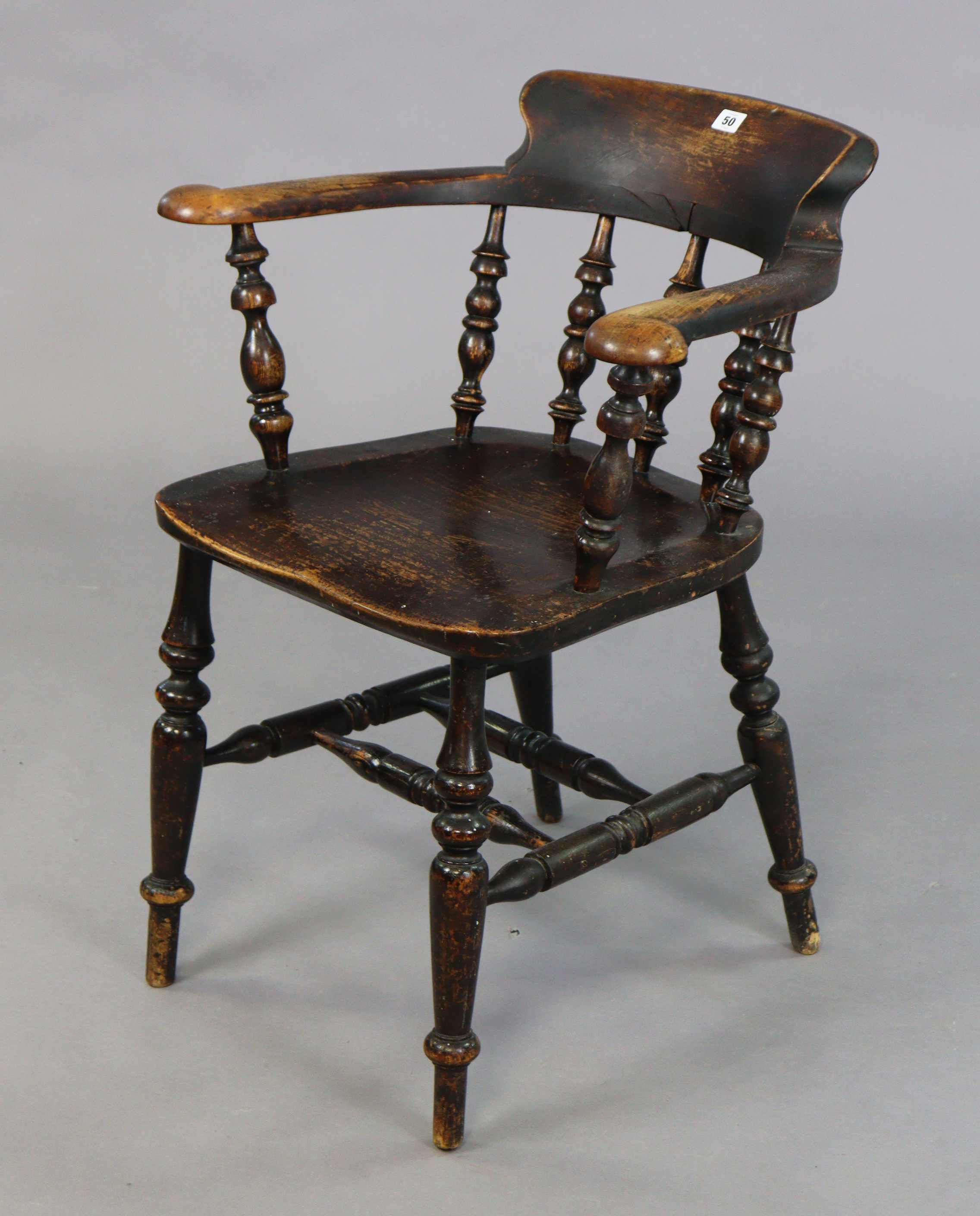 A spindle-back captain’s chair with a hard seat, & on four turned legs with spindle stretchers.