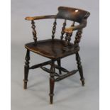 A spindle-back captain’s chair with a hard seat, & on four turned legs with spindle stretchers.