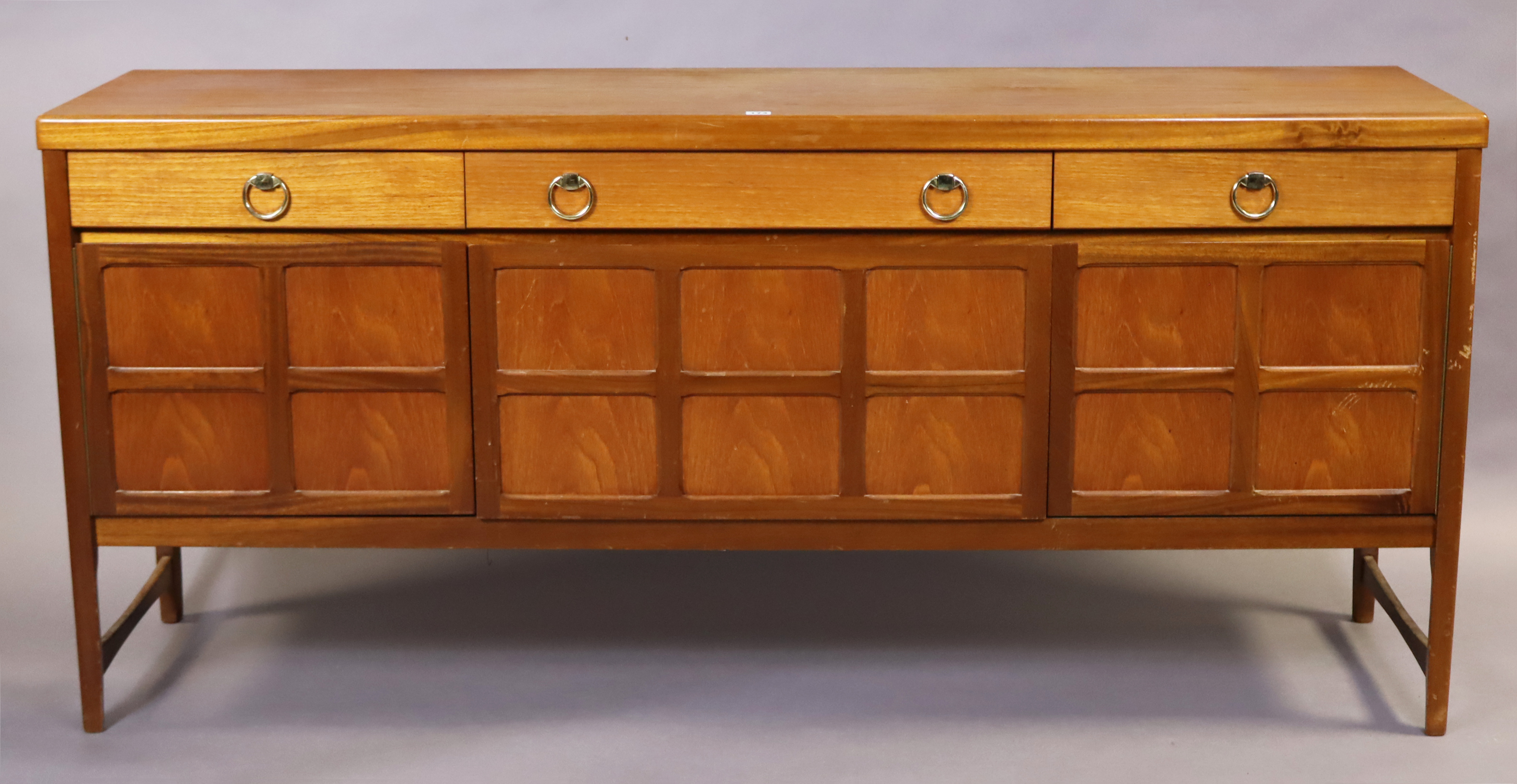 A Nathan teak sideboard fitted three frieze drawers above cupboards enclosed by a fall-front panel