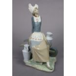 A Lladro porcelain figure of a milkmaid seated on a wheelbarrow, 32.5cm high.