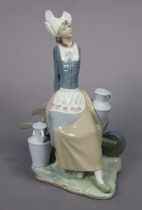 A Lladro porcelain figure of a milkmaid seated on a wheelbarrow, 32.5cm high.