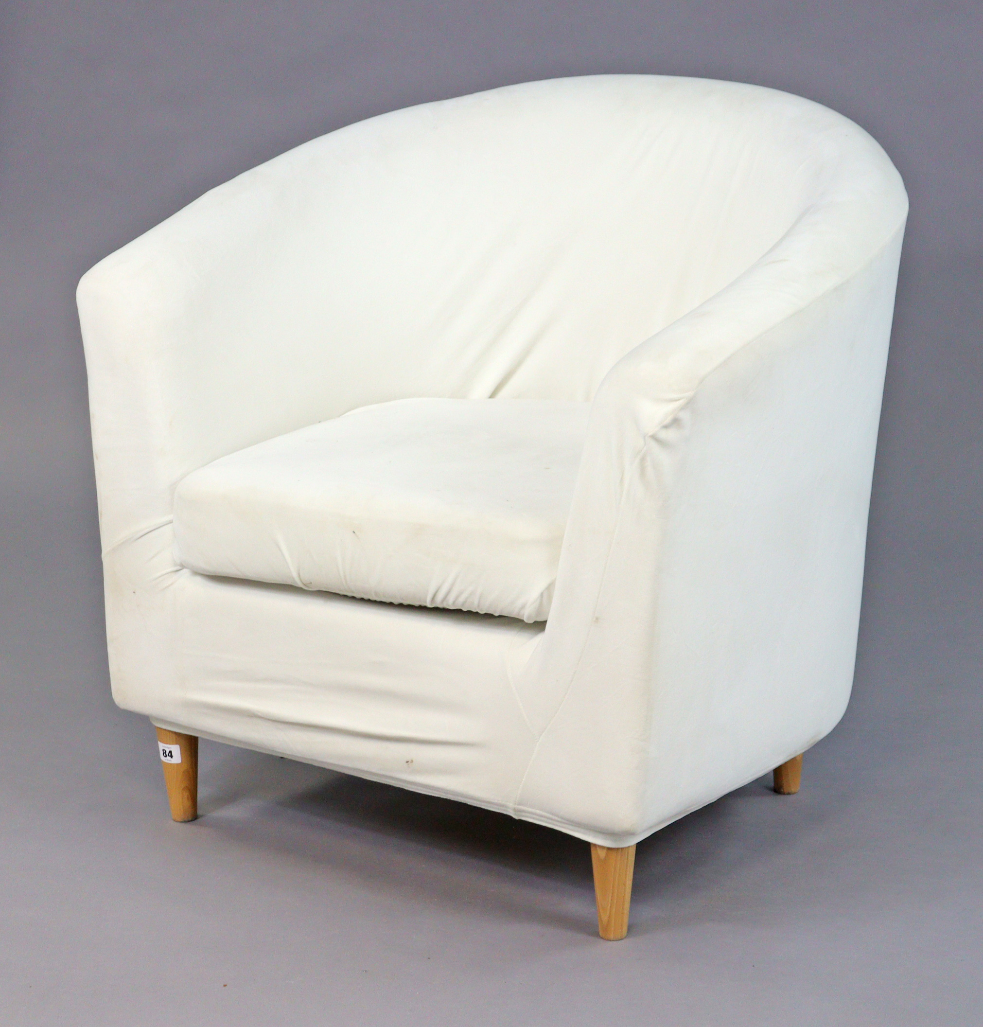 An Ikea tub-shaped chair upholstered off-white material, & on four round tapered legs.