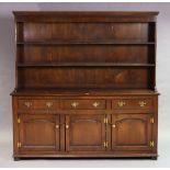 A Georgian-style oak dresser the upper part with three open shelves & having a panelled back, the