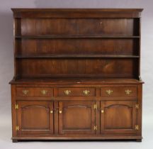 A Georgian-style oak dresser the upper part with three open shelves & having a panelled back, the