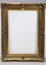 A large gilt-finish picture frame with a raised scroll & pierced border & with a beaded edge, 91cm x