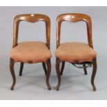 A pair of 19th century mahogany dining chairs each with an open kidney-shaped back, padded seat, &