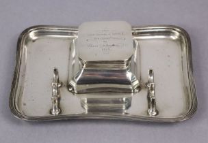 A George V silver rectangular inkstand with reeded rim, penholder, engraved inscription to the