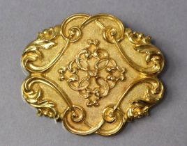 A Victorian yellow metal hollow-work brooch of shaped oval form, with bright scroll decoration on