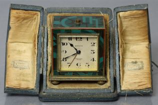 An Art Deco Zenith travelling alarm clock in gilt brass rectangular case with enamelled geometric