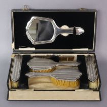 A George V engine-turned silver mounted dressing table set of hand mirror, two hairbrushes, two
