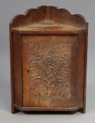 A late 19th/ early 20th century oak small hanging corner cupboard, enclosed by a panel door with