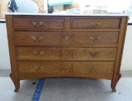 A late 19thC Continental light oak, five drawer commode with a white marble top, raised on carved,