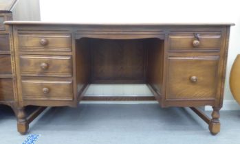 An Ercol mid brown beech and elm framed panelled, twin pedestal, kneehole desk, comprising an