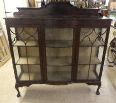 A 1930s mahogany breakfront bow front display cabinet, raised on stubby cabriole legs, talon and