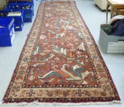 A Persian runner, decorated with repeating stylised designs, on a mainly red ground  45" x 168"