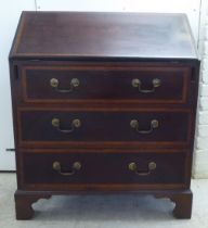 An Edwardian crossbanded, ebony inlaid mahogany bureau, the fall flap over three drawers, raised