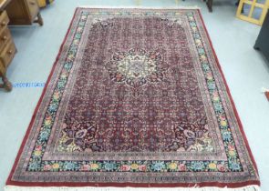 An Indian rug, profusely decorated with repeating floral and other stylised designs, on a mainly red