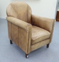 An Art Deco inspired soft brown hide upholstered enclosed armchair, raised on tapered legs