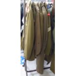 Six British Army uniforms: to include a greatcoat; and tunics (Please Note: this lot is subject to