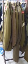Six British Army uniforms: to include a greatcoat; and tunics (Please Note: this lot is subject to
