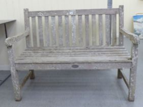 A two person teak garden bench of slatted construction  48"w