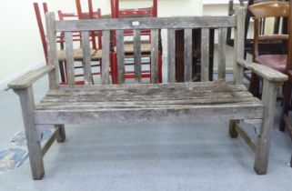 A two person teak garden bench of slatted construction  48"w