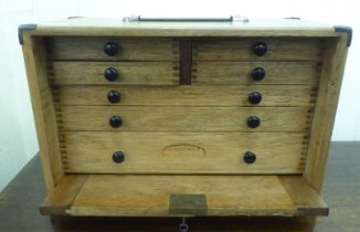 A mid 20thC oak engineer's tool chest, the removeable front panel enclosing seven drawers  11"h