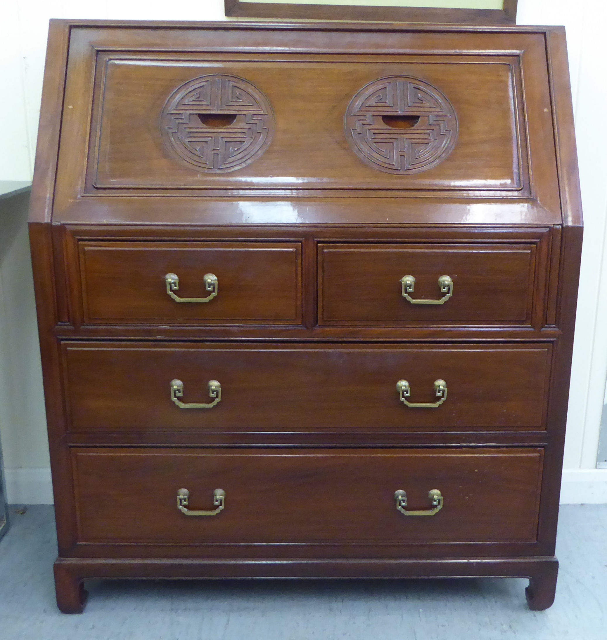 A modern Chinese fruitwood bureau with a fall flap, over two short/two long drawers, raised on block