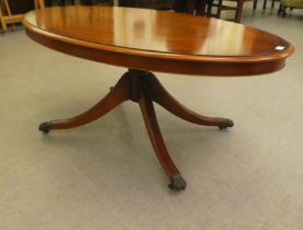 A modern mahogany finished coffee table, raised on a splayed pedestal base  21"h  49"w
