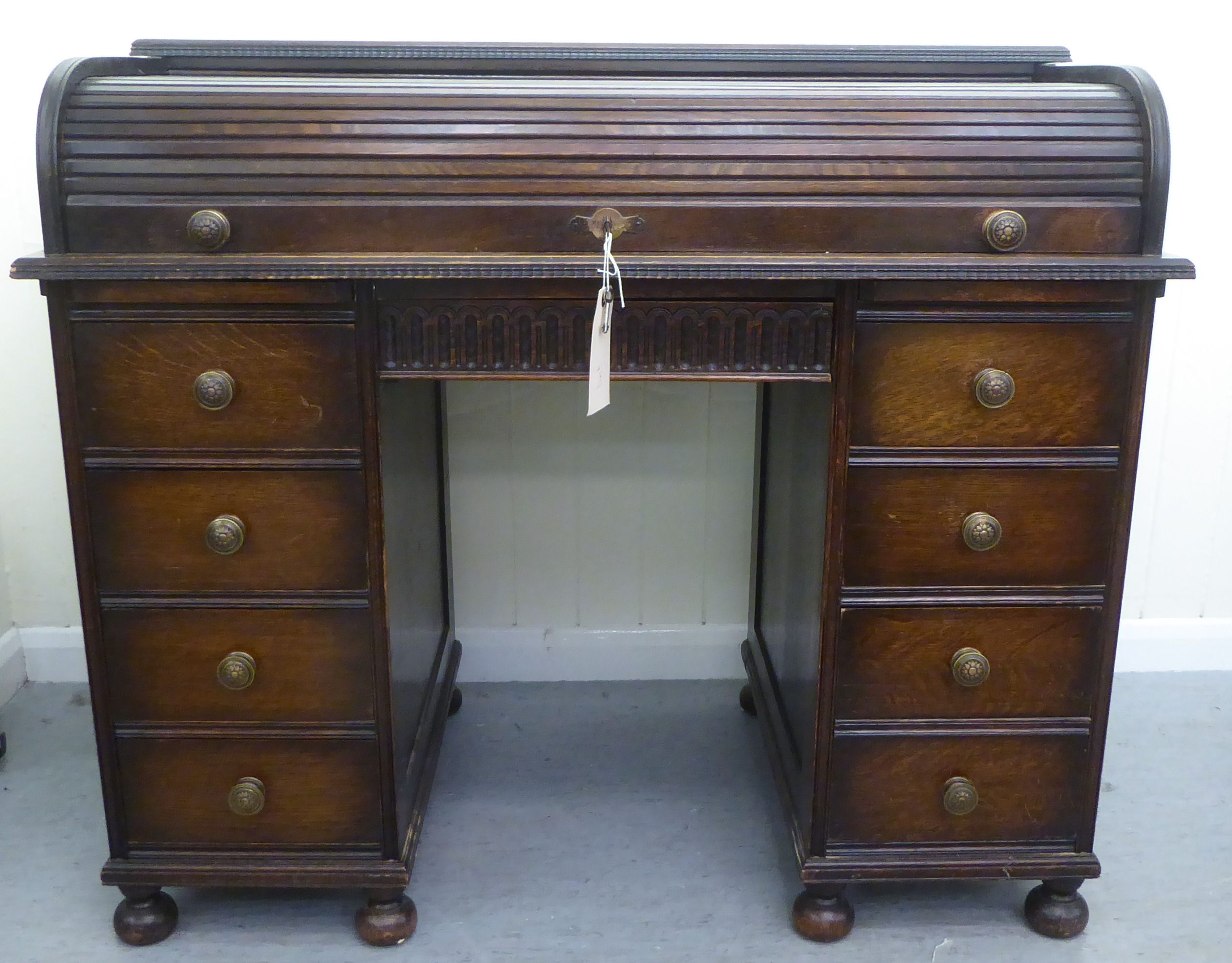 A 1930s oak roll top desk with twin pedestals, comprising an arrangement of eight drawers, raised on
