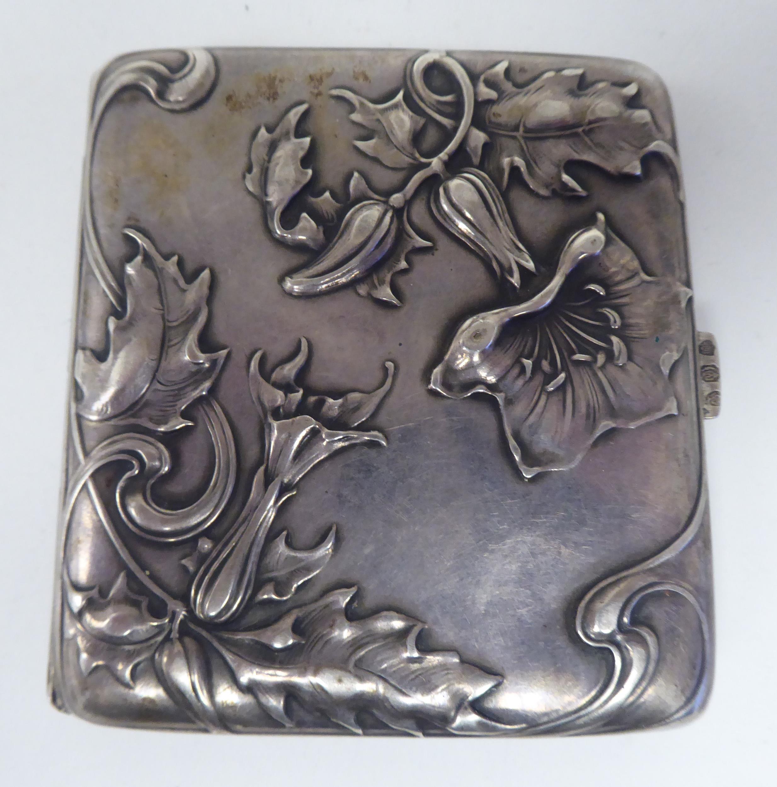 An Art Nouveau silver coloured metal, folding cigarette case, on a button clasp, embossed and chased