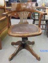 An early 20thC oak framed revolving desk chair, raised on a splayed pedestal base