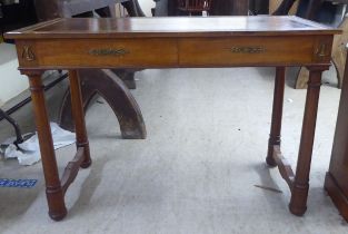 A mid 20thC Continental style mahogany writing table with a tooled and gilded old gold coloured hide