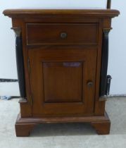 A modern panelled mahogany cupboard with a box drawer, over a door, flanked by recessed pillars,