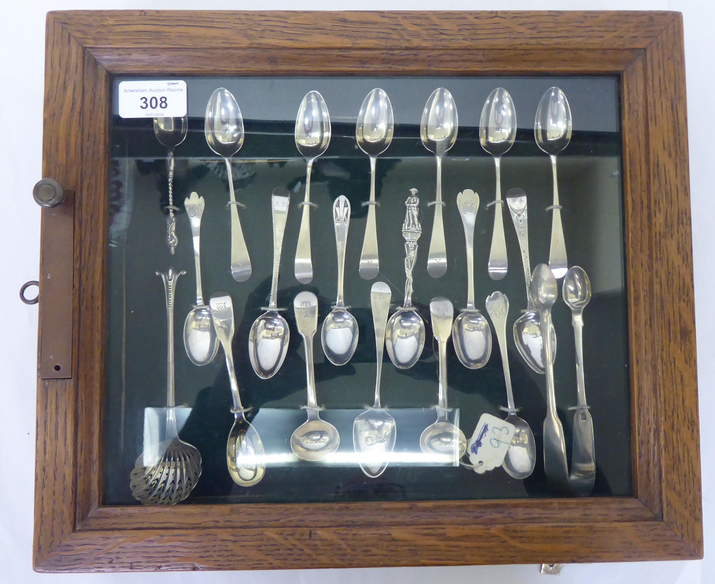 A presentation case with a deep set, glazed oak door, containing silver teaspoons