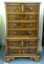 A modern yew finished bedside chest with an arrangement of four short/four long drawers, raised on