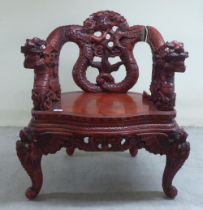 A 20thC Sino-European red stained and profusely carved round back chair, featuring entwined dragons,