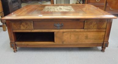 A modern walnut finished coffee table with an arrangement of three drawers, raised on block feet